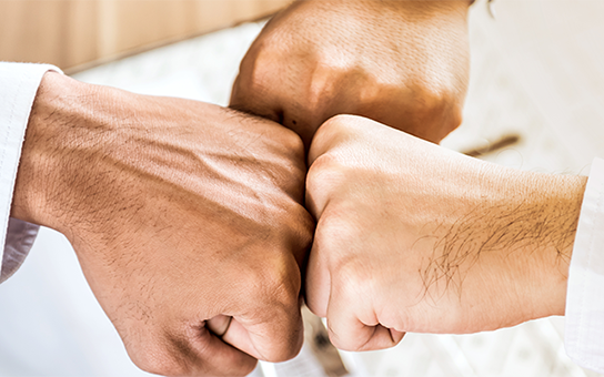 チームワークを誓って拳を突き合わせるメンバー